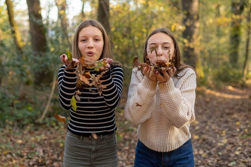 Jeunes filles soufflant des feuilles sèches dans les bois