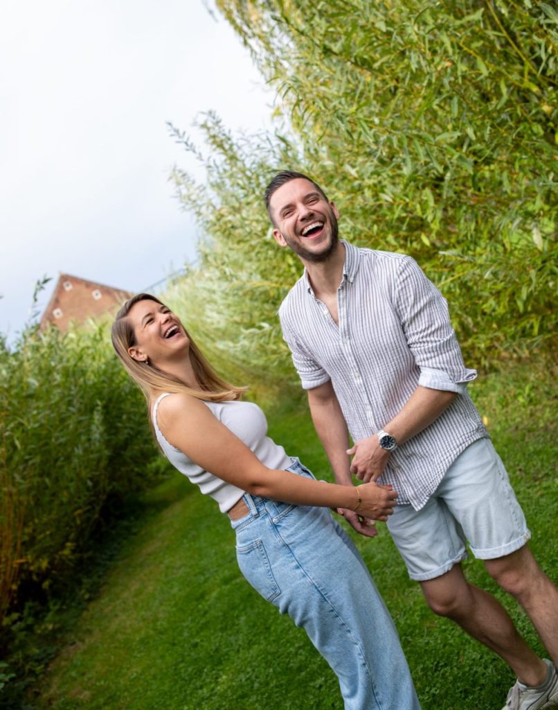Couple qui rit aux éclats pendant une séance photo de couple dans un parc